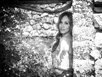 Portrait of smiling woman standing by stone wall