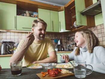 Portrait of smiling father and daughter having food at home