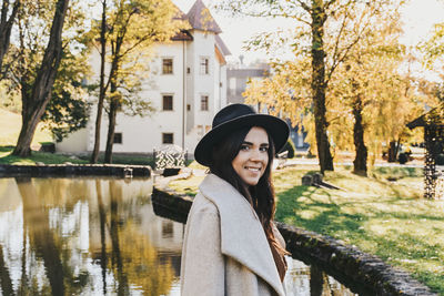 Young woman in fall clothes, coat, hat. looking at camera, smiling.