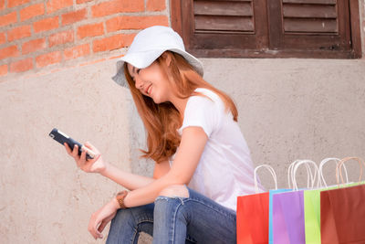 Young woman using mobile phone while shopping in city