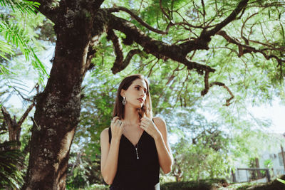 Portrait of young woman standing against trees