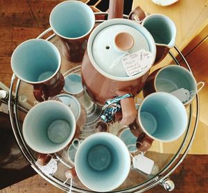 High angle view of teapot and cups for sale on glass table