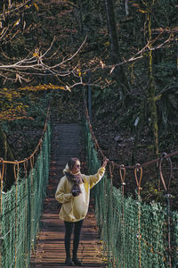 Young woman standing on footbridge in forest