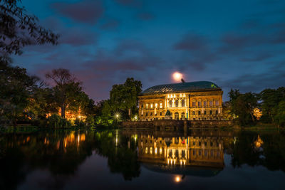 Landmark downtown administration building reflecting on calm water in quiet blue night