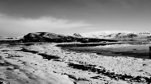 Scenic view of sea by snowcapped mountain against sky