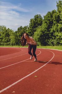 Full length of woman running on field against trees