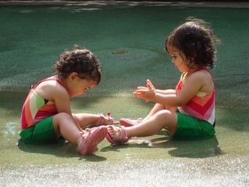 Twin baby girls playing in water on floor