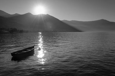 Boat moored in lake against mountains on sunny day