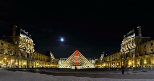 Illuminated buildings against sky at night