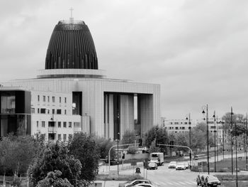 Modern church building in city against cloudy sky