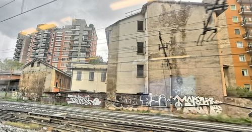 Railroad tracks by buildings against sky