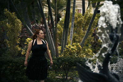 Woman standing by tree in forest