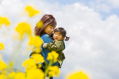 Close-up of mother and woman against yellow sky