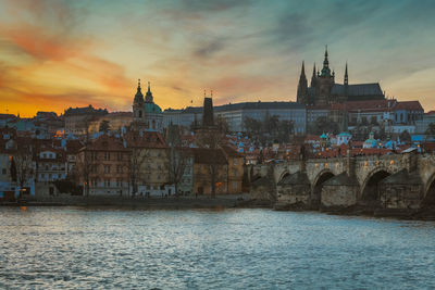 View of buildings at waterfront against cloudy sky