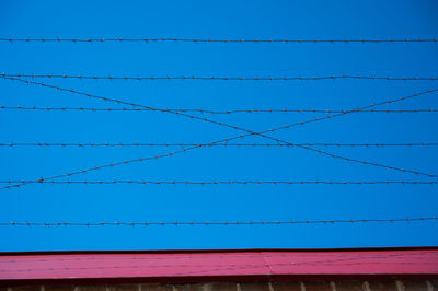 Low angle view of power lines against clear blue sky