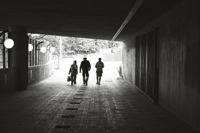 Rear view of silhouette people walking on footpath in tunnel