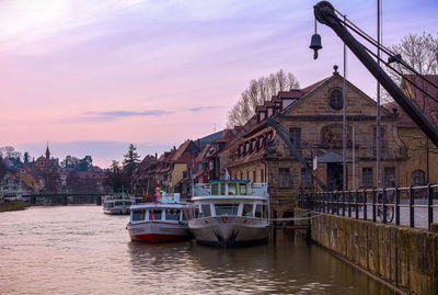 Boats moored at canal against sky during sunset