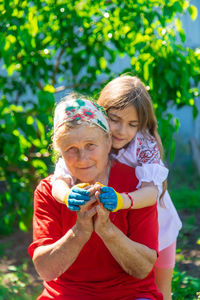 Portrait of smiling young woman standing against plants