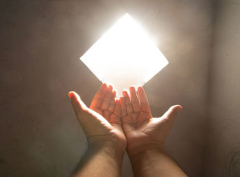 Close-up of praying hand holding illuminated light