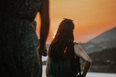 Rear view of woman standing against sky during sunset