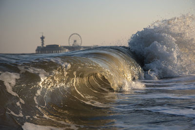 Close-up of waves splashing on shore against clear sky