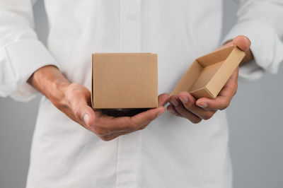 Midsection of man holding paper while standing against wall