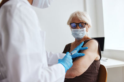 Doctor vaccinating senior woman at clinic