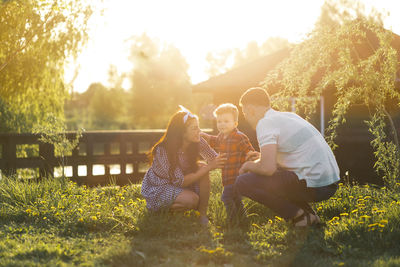 Rear view of couple kissing on field during sunset