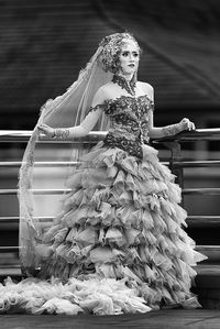 Young woman in dress standing on footpath by railing