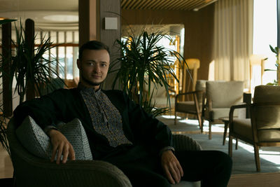 Portrait of young man sitting on chair at home