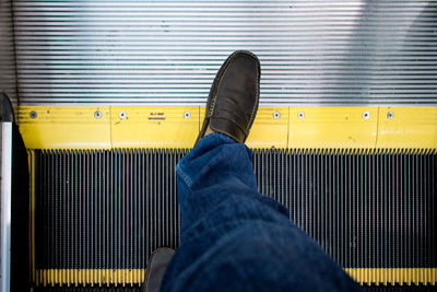 Low section of man standing on escalator