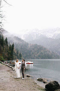 Women standing by lake against sky