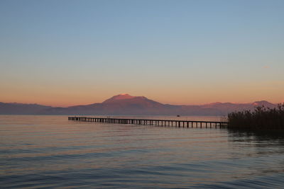 Scenic view of lake against clear sky during sunset