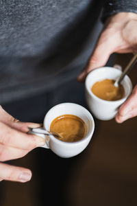 Midsection of man holding espresso coffee cup