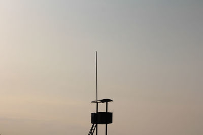 Low angle view of silhouette bird perching on street light against sky