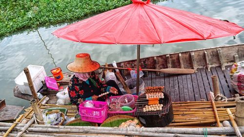A seller is preparing meatballs for sale in a boat.
