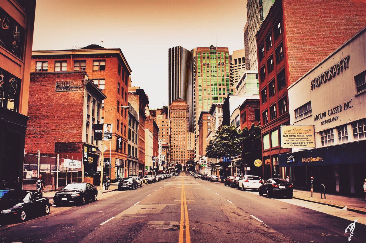 building exterior, architecture, built structure, transportation, the way forward, city, street, car, diminishing perspective, road, land vehicle, vanishing point, city street, city life, road marking, building, mode of transport, sky, residential building, residential structure