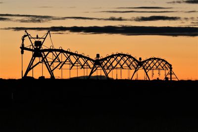 Silhouette cranes against sky during sunset