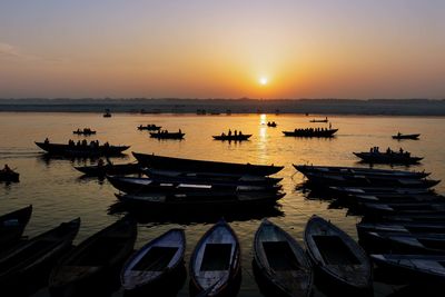 Boats moored on sea against sky during sunset