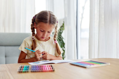 Girl with braids chooses bright felt-tip pen to draw picture