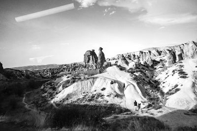 People standing on rock against sky