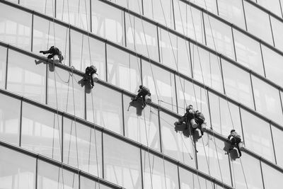 Low angle view of worker washing building window during sunny day