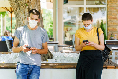 Portrait of man with woman using smart phone standing outdoors