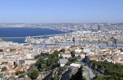 High angle view of townscape by sea against clear sky