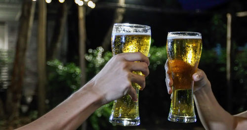 Cropped hands of friends toasting beer glasses
