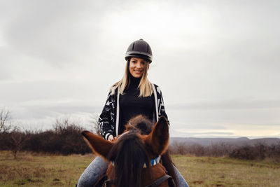 View of woman wearing helmet riding horses on field