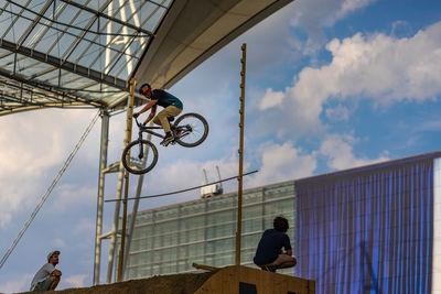 Low angle view of men on bicycle against sky