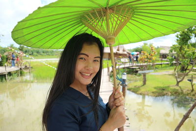 Portrait of smiling woman holding lake in park