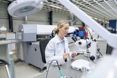 Scientist sitting at desk with microscope in industry