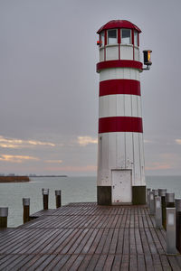 Lighthouse by sea against sky